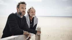 Ein Vater und sein erwachsener Sohn schauen aufs Meer