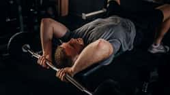 Ein Mann auf einer Hantelbank, der eine Trizeps-Übung durchführt