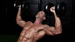 Ein trainierter Mann trainiert oberkörperfrei mit Kurzhanteln Ein trainierter Mann trainiert oberkörperfrei mit Kurzhanteln