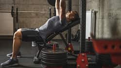 Sports man doing bench press, athlete during training in professional gym, lifting weights for biceps, pectorals and back muscles Sports man doing bench press, athlete during training in professional gym, lifting weights for biceps, pectorals and back muscles