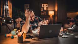 Ein verzweifelter Vater sitzt mit seinem Baby am Rechner