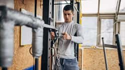 Ein junger Mann bereitet im Fitnessstudio Ketten für sein Training vor