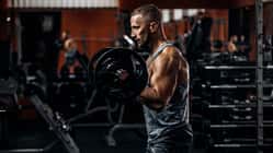 Muskulöser Mann im Fitnessstudio beim Langhantelheben