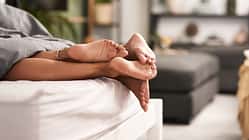 Shot of a couple’s feet poking out from under the bed sheets