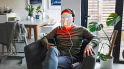 Ein Mann sitzt im Sessel mit einer LED-Maske fürs Gesicht 