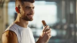 Ein glücklicher Sportler isst einen Proteinriegel