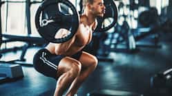 Ein Mann führt Kniebeugen mit einer Langhantel aus im Gym