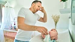 Vater wickelt sein Baby und hält sich die Nase zu