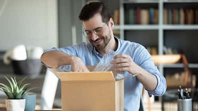 Smiling,Man,Wearing,Glasses,Unpacking,Awaited,Parcel,,Looking,Inside,,Sitting