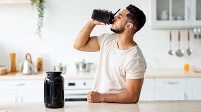 Young,Arab,Guy,Drinking,Protein,Shake,From,Bottle,At,Kitchen,