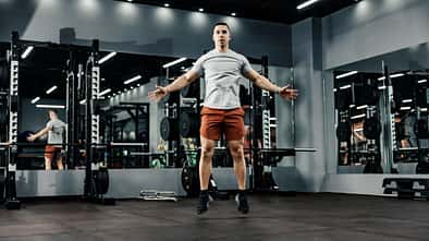 Sportler macht Hampelmänner im Fitnessstudio