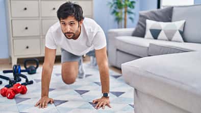 Mann macht im Wohnzimmer Fitnessübungen.