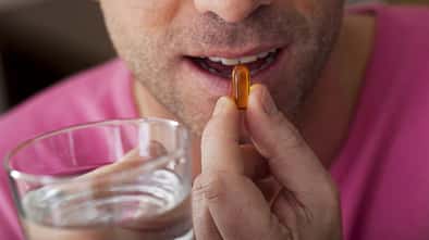 Mann schluckt ein Omega-3-Supplement.