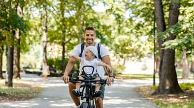 Vater fährt mit seinem Kind im Kindersitz Fahrrad