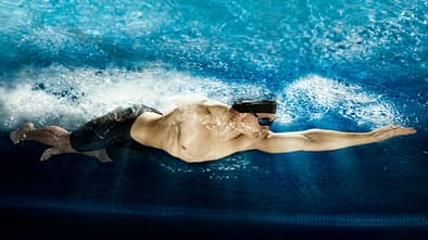 Mann krault athletisch durch einen Pool 