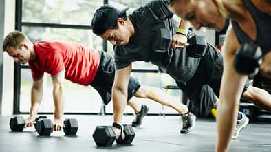 Group of friends doing pushups with dumbbells