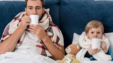 Ein Vater und sein Sohn liegen krank im Bett