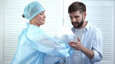 Eine Krankenschwester übergibt einem Vater sein neugeborenes Kind