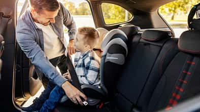 Vater setzt sein Kind in den Kindersitz