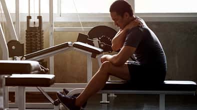 Mann hält sich die schmerzende Schulter im Gym.