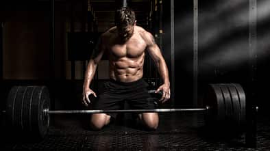 Mann vor schwer beladener Langhantel.