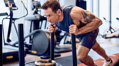 Superstar Jason Fox schiebt einen Gewichtsschlitten im Gym.