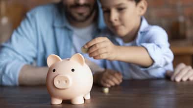 Vater und Sohn stecken Geld in ein Sparschwein