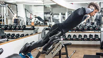hyperextension Young handsome fit man performing back-extension exercise on roman chair at gym.