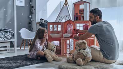 Vater und Tochter spielen mit einem Puppenhaus