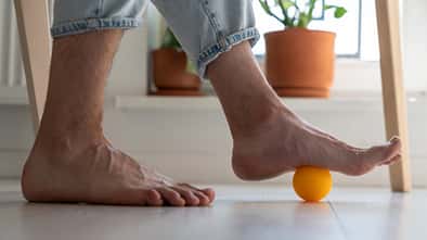 Mann rollt über Faszienball mit Füßen
