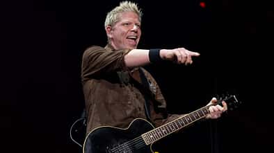 Dexter Holland singt auf der Bühne und hält eine Gitarre