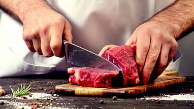 Mann schneidet rohes Rindfleisch
