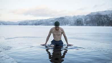 Man swimming in frozen lake