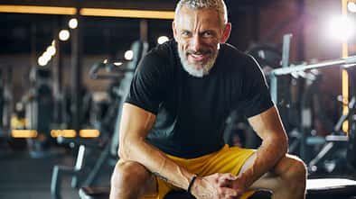 Sportsman with a happy smile sitting on the weight bench