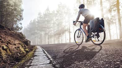 Ein junger Mann fährt auf dem Fahrrad über eine Landstraße