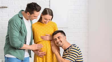 Zwei Männer kümmern sich um eine schwangere Frau