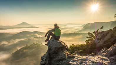 Die Silhouette eines Mannes beim Wandern auf dem Bergrücken auf dem Gipfel der Wolken