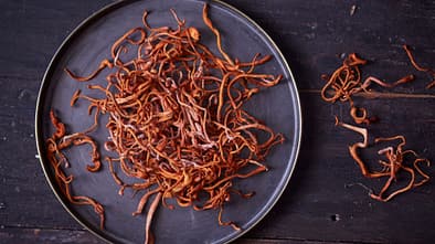 Vitalpilz Cordyceps auf einem schwarzen Teller