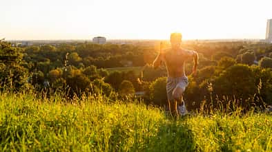 Mann rennt bei Sonnenuntergang über eine Wiese
