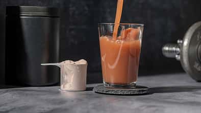 Schokoladen Proteinshake wird in ein Glas geschüttet