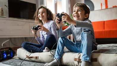Zwei Kinder sitzen vor einem Fernseher und daddeln