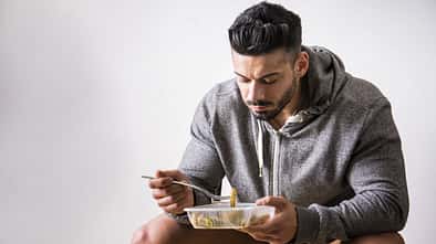 Hungry,Muscular,Young,Man,Gulping,Down,Food,Looking,At,Plastic