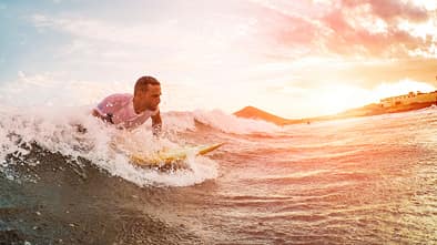 Male athlete surfing at sunset - Surfer man performing outdoor inside ocean- Extreme sport, competition, travel and summer vacation concept - Soft focus on man head