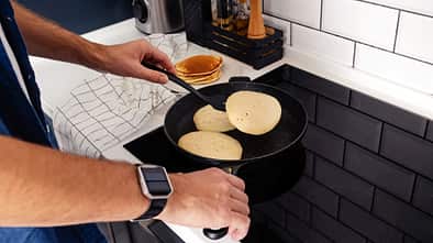 Mann brät Pancakes in der Pfanne