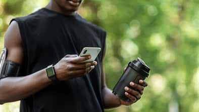Mann hält einen Shaker in der Hand und schaut auf sein Handy