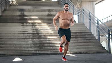 Mann joggt oberkörperfrei eine Treppe runter