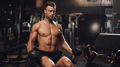 Determined young man lifting up dumbbells in the gym