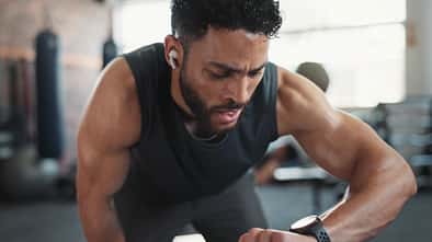 Ein Mann in Sportkleidung schaut auf seine Fitnessuhr