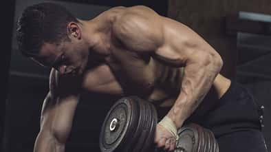 Ein Mann trainiert seine Arme mit einer Kurzhantel Ein Mann trainiert seine Arme mit einer Kurzhantel