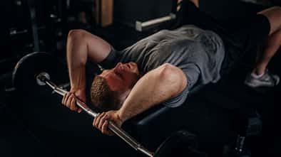 Ein Mann auf einer Hantelbank, der eine Trizeps-Übung durchführt